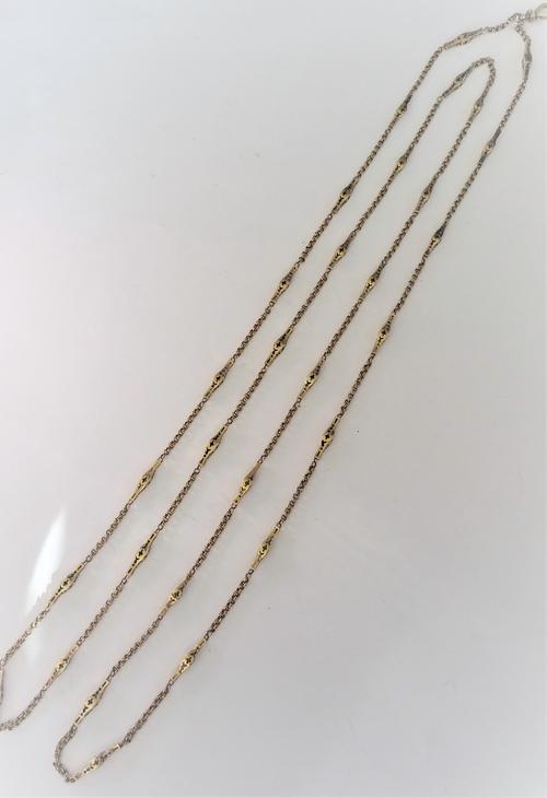 A gold long guard muff chain in a twin circular and pierced bar link design, the front fitted with a swivel clasp, length 136cm, weight 21.7 gms.