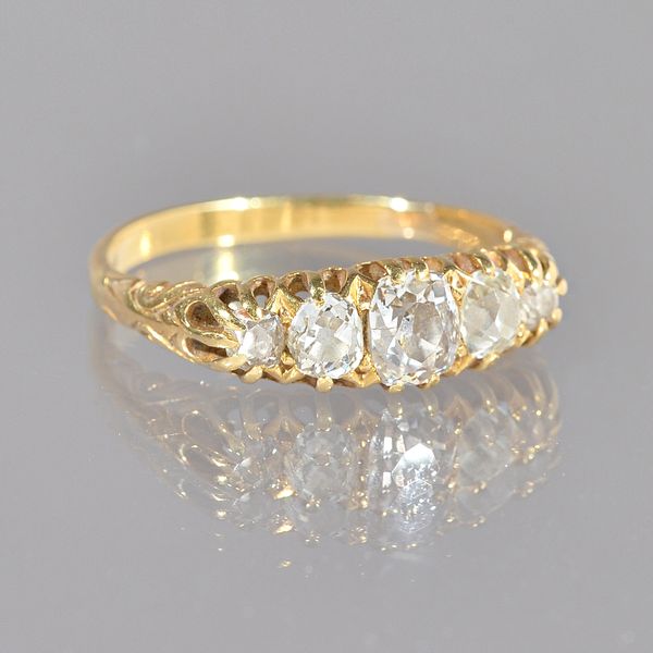 A gold and diamond five stone ring, claw set with a row of cushion shaped diamonds graduating in size to the centre stone, the mount decorated with sc