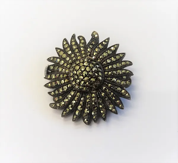 A silver and marcasite set brooch watch, designed as a single flowerhead, the centre opening to reveal a watch compartment, the silvered dial with bla