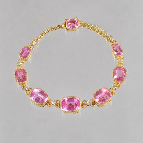 A gold, pink tourmaline and diamond bracelet, mounted with seven graduated cushion shaped pink tourmalines alternating with eight circular cut diamond