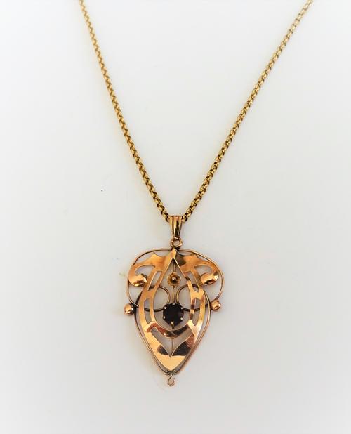 A gold and amethyst set single stone pendant, in a pierced scrolling design, with a small flowerhead motif, detailed 9 CT, on a 9ct gold circular link