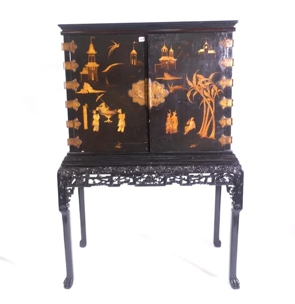 An Edwardian chinoiserie japanned cabinet-on-stand, incorporating 18th century Japanese lacquer doors, the exterior decorated with figures, palm trees