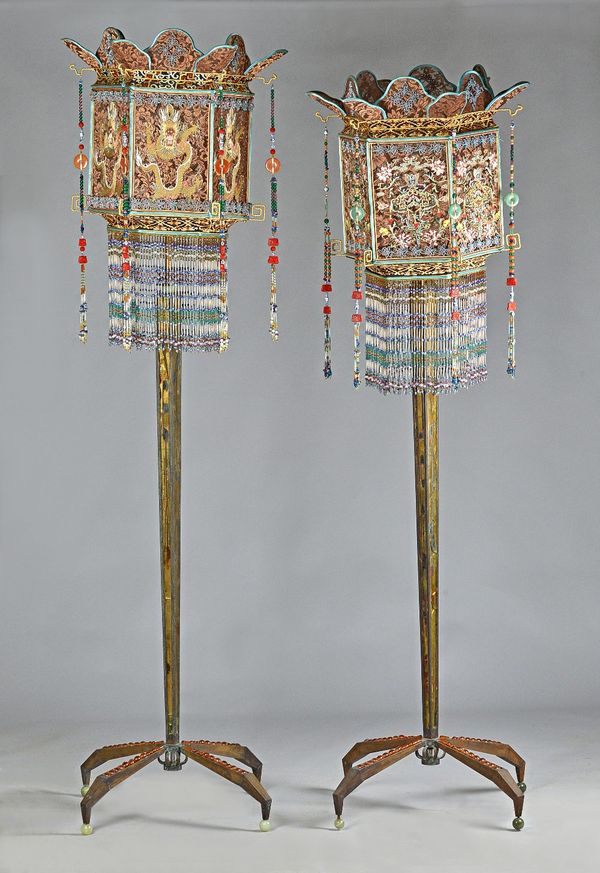 A pair of unusual and decorative standard lamps, each with Chinese pierced dragon shade above reverse painted glass tapering stem on four amber glass