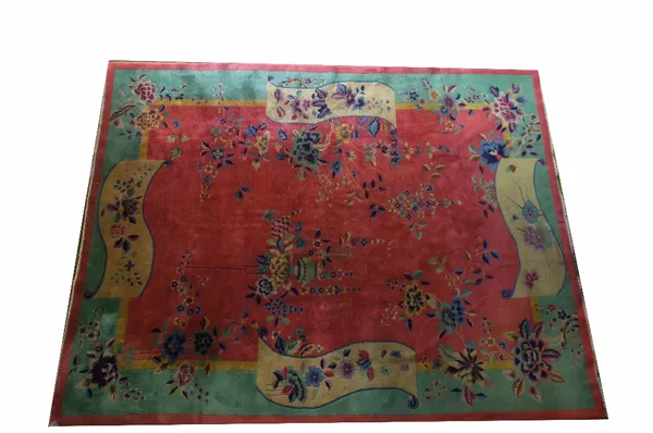 A Chinese carpet, circa 1930, the iron red central field with decoration of polychrome sprays of flowers within mint green main border and gold panels