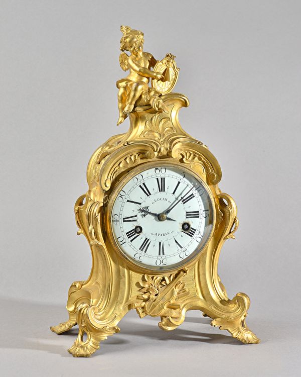 A LOUIS XV ORMOLU MANTEL CLOCKBy Lacan, Paris, circa 1760The shaped case surmounted with a seated cherub holding a sundial, above foliate scroll panel