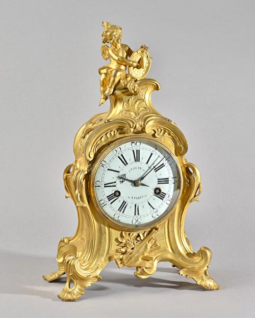 A LOUIS XV ORMOLU MANTEL CLOCKBy Lacan, Paris, circa 1760The shaped case surmounted with a seated cherub holding a sundial, above foliate scroll panel