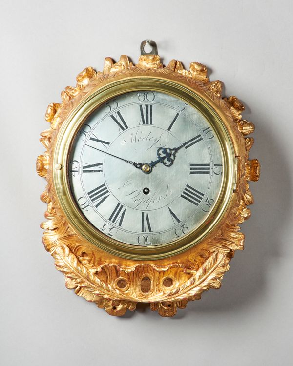 A GEORGE III GILTWOOD WALL TIMEPIECEBy Heeley, Deptford, circa 1765The circular-shaped carved mahogany case with foliage above a pierced apron, cast b