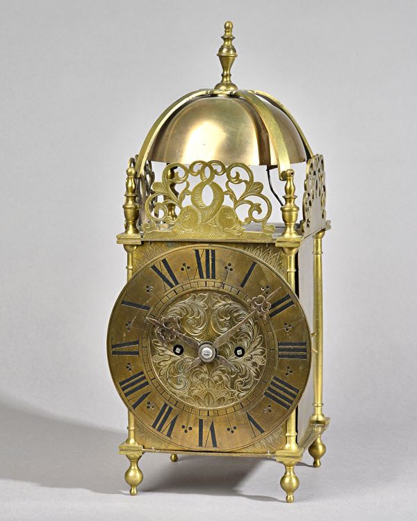 A BRASS QUARTER-STRIKING LANTERN CLOCKCirca 1910The case of typical form, surmounted by a bell and strapwork with turned finial, with brass chapter ri