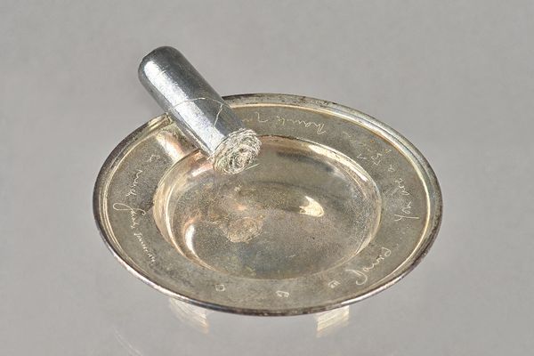 A silver ashtray, the side applied with a cast model of a lit cigar, presentation inscribed Theo Fennell, London 1993.   Provenance; property from the