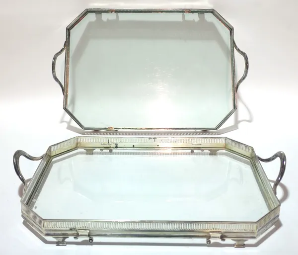 A pair of silver plated twin handled drinks trays, each with pierced gallery border and glass bases, 52cms wide, 32cms deep. (2)  Provenance; property