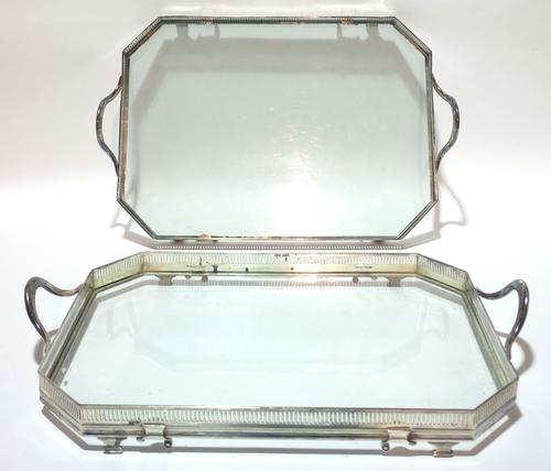 A pair of silver plated twin handled drinks trays, each with pierced gallery border and glass bases, 52cms wide, 32cms deep. (2)  Provenance; property