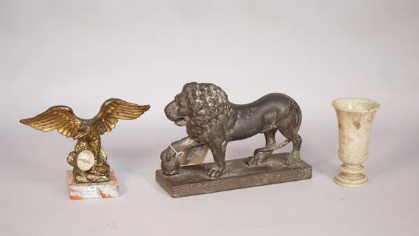 A 19th century cast iron 'lion' doorstop, with front paw raised on a ball, 23.5cm, a gilt metal eagle on a marble plinth, 14cm high and a 20th century