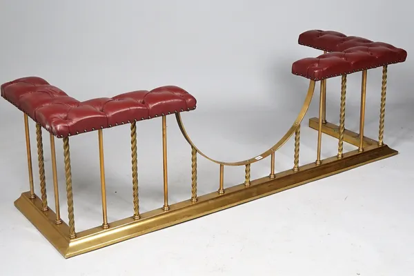 A Victorian style brass and burgundy leather upholstered club fender, with button back detail and spiral twist rails over a stepped kerb, 189cm wide.