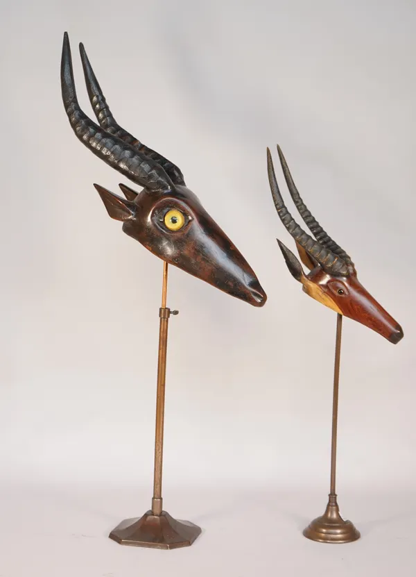 A Black Forest style hardwood carved antelope with glass eyes on an adjustable metal stand, 60cm high and another similar smaller, (2).