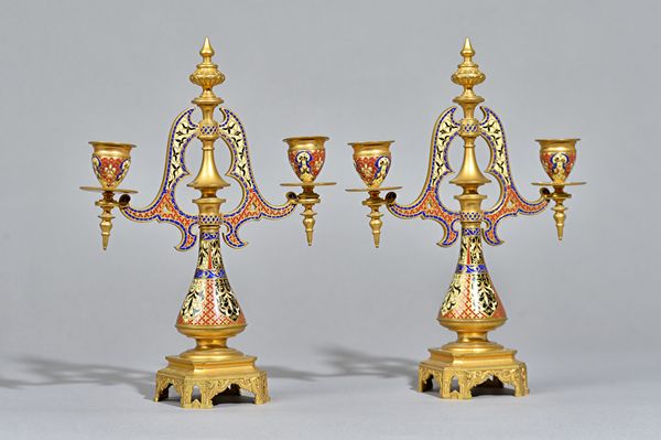 A pair of French champlevé brass twin branch candelabra, late 19th century, of Gothic architectural form, 30cm high, (2). Illustrated