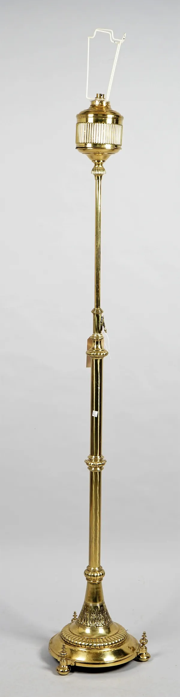 A gilt metal mounted brass standard lamp, early 20th century, with adjustable top over a circular base and three pad feet.