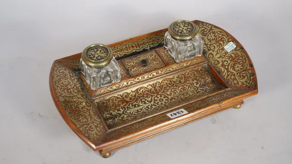 A Regency mahogany and brass inlaid inkwell, with twin glass lidded bottles and pen recess on four brass feet, 36cm wide.