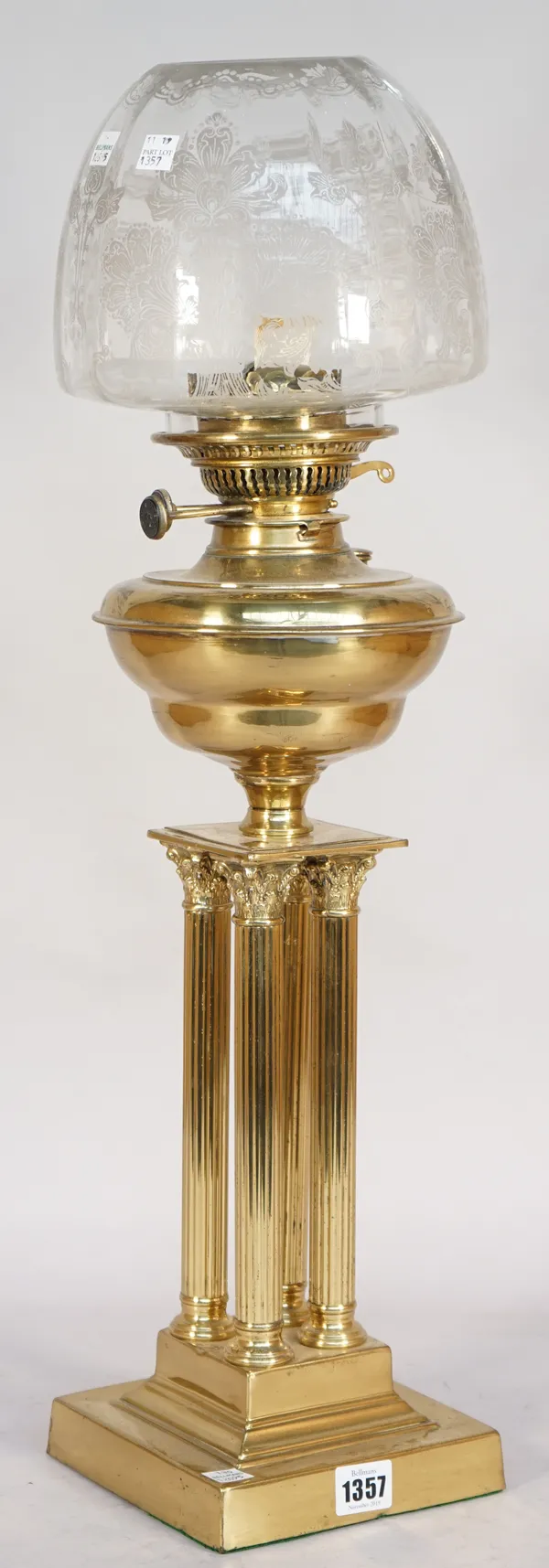 A brass oil lamp, early mid-20th century, of quadruple Corinthian column form on a stepped square base, with later etched glass shade, 66cm high.