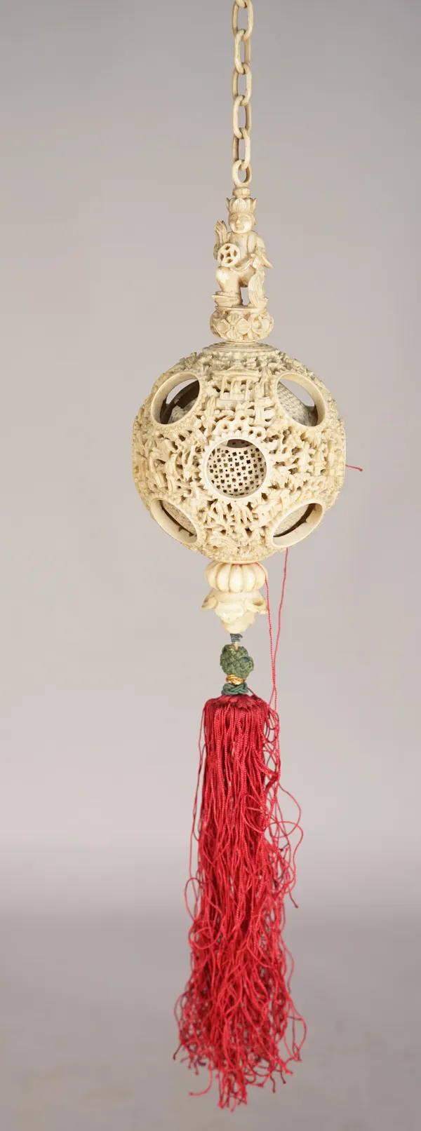 A late 19th century Chinese ivory hanging puzzle ball, profusely carved and pierced with figures and fauna, (a.f.), 8cm diameter.