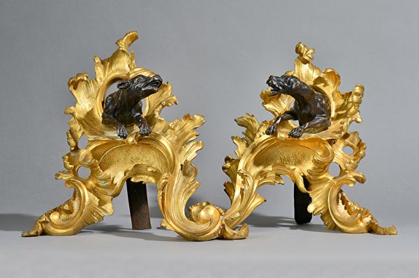 A pair of French ormolu and patinated bronze chenets, second half 19th century, each modelled with a snarling dog emerging from a pierced scrolling ac