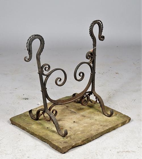 A Victorian wrought iron boot scraper of scroll work form, raised on four shaped feet and a stone plinth, 62cm high.