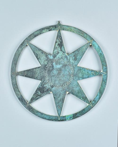 A patinated bronze surveyor's marker, late 19th century, of circular form engraved with compass markers to an eight-pointed central star, engraved to
