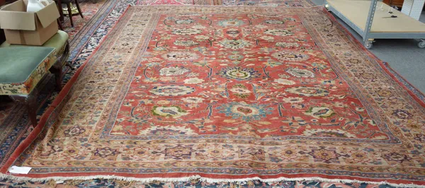 A Fereghan carpet, Persian, the madder field with a bold all over palmette and floral vine design, an ivory star medallion border, 416cm x 330cm.