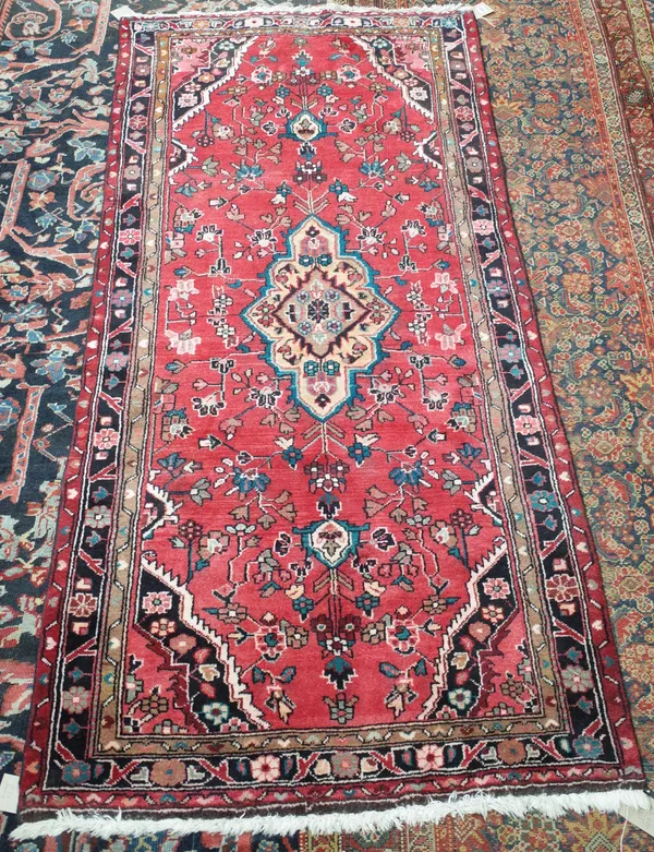 A Hamadan rug, Persian, the madder field with an oranage medallion, spandrels, all with angular floral sprays, 207cm x 100cm.