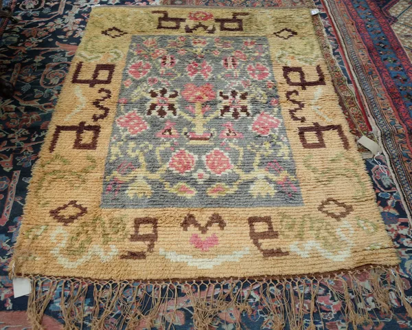 A Rya rug, Swedish, the grey field with a stylised flowering plant and other flower heads; a wide golden border, 165cm x 132cm.