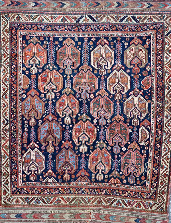 An Afshar rug, South Persian, the indigo field with rows of boteh flowerheads, supporting flowers; an ivory flower border; 132cm x 102cm. Illustrated