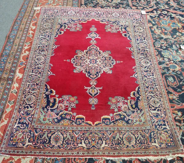 A Kashan rug, Persian, the plain madder field with a central medallion, matching spandrels; a complementary indigo border, 193cm x 130cm.