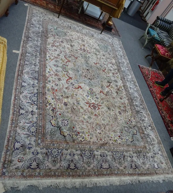 A Chinese silk carpet, the ivory field with a bold central medallion, matching spandrels, all with scrolling floral vines; an indigo and ivory waved b