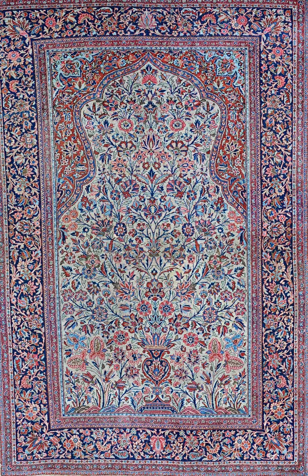 A Kashan prayer rug, Persian, the fawn mehrab with a vase filled with abundantly floral sprays, a madder arch above an indigo floral spray border, 205