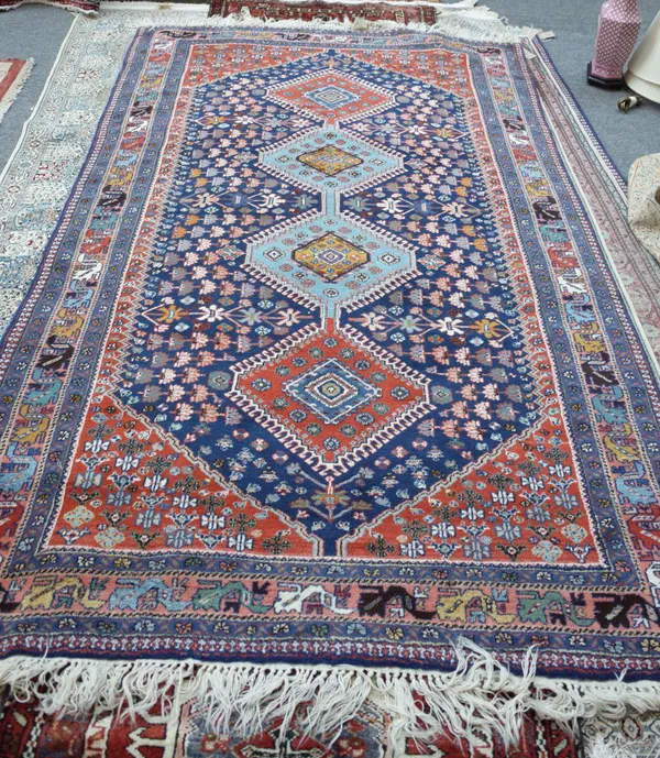 A Shiraz rug, Persian, the indigo field with two indigo and two madder medallions, all with flower heads, madder spandrels, a pale madder stylised lea