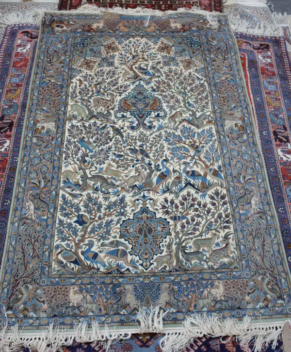 A fine Ghom part silk tree of life rug, Persian, the ivory field with bold indigo medallions flowering tress filled with exotic birds, wolves and deer