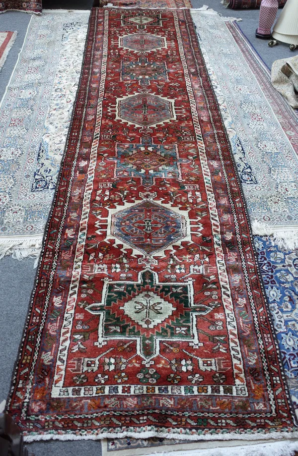 A Kasajar runner Persian, the madder field with seven bold medallions, flowerheads, a grey trailing flowerhead border, 384cm x 97cm.