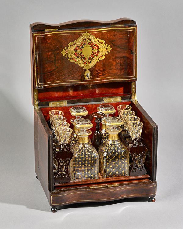 A 19th century French brass inlaid rosewood table top liqueur cabinet, the serpentine lift-top revealing four decanters and sixteen glasses contained