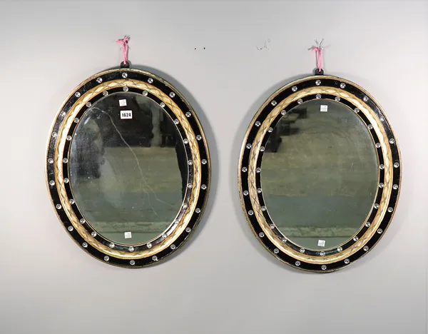 A pair of 19th century Irish oval mirrors, the parcel gilt ebonised frames with facet decoration, 47cm wide x 57cm high.