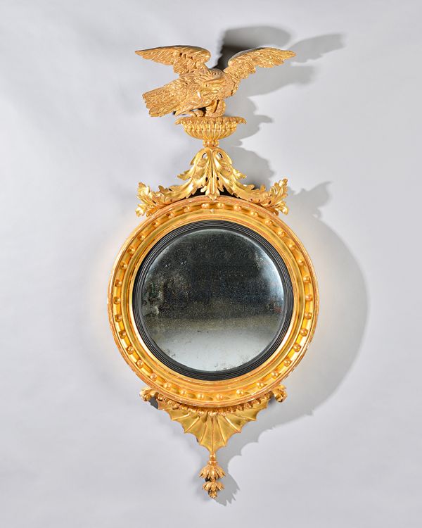 A William IV gilt framed convex mirror with eagle crest and star burst lower frieze, the ball mounted frame with ebonised slip, 65cm wide x 140cm high