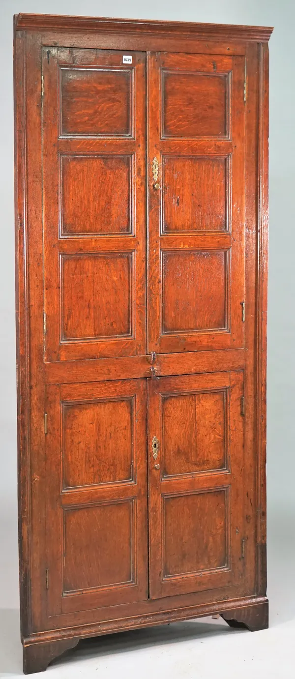 An 18th century oak floor standing double height corner cabinet with two pairs of double panel doors on bracket feet, 92cm wide x 198cm high.