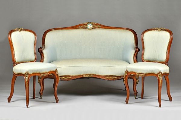 A late 19th century gilt-metal mounted yew wood framed tub back sofa with ceramic plaque inset hump crest over double serpentine seat and scroll suppo