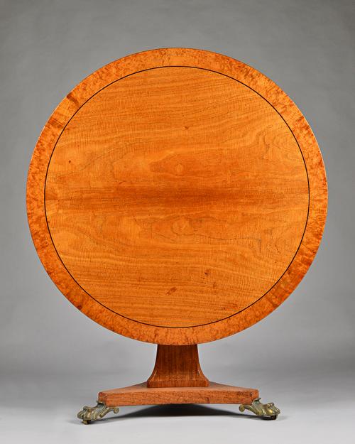 A Regency burr elm banded figured ash breakfast table, the circular snap top on canted triangular column and three gilt bronze paw feet, 120cm diamete