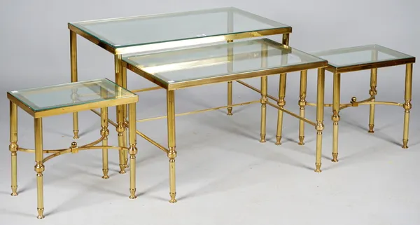 A nest of four mid-20th century lacquered brass and glass inset occasional tables, on semi reeded supports, the largest 72cm wide x 46cm high.