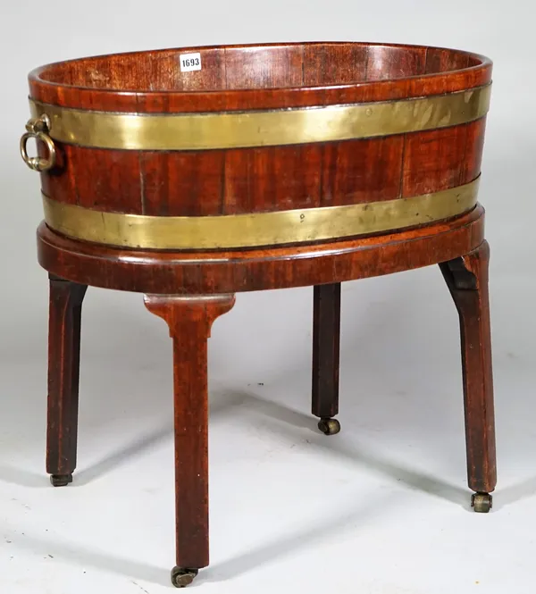 An 18th century brass cooper banded oval wine cooler with loop handles on canted square supports, 65cm wide x 59cm high.