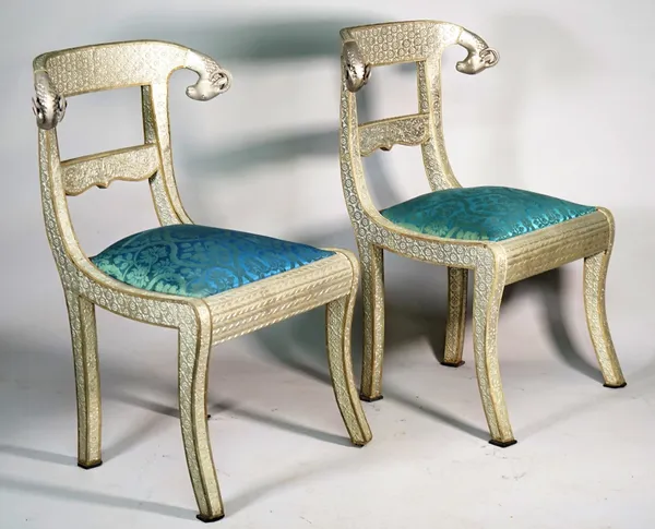 A pair of Anglo Indian style metal veneered side chairs with rams head finials on sabre supports, 62cm wide x 86cm high.