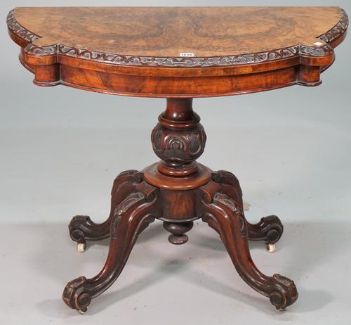 A Victorian figured walnut card table, the pivoting shaped semi elliptic top on carved bulbous column and four downswept supports, 91cm wide x 71cm hi