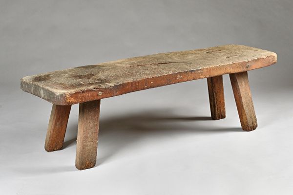 A 19th century pig bench, the rectangular elm slab top on four stake supports, 145cm wide x 43cm high. Illustrated