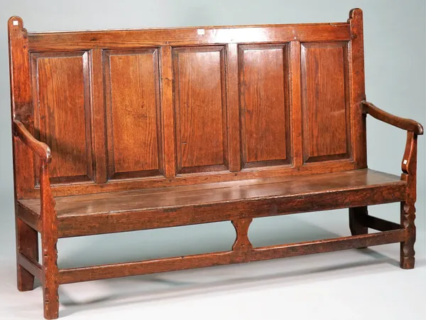 An 18th century oak settle with five panel back and open arms on canted block supports, 167cm wide x 110cm high.