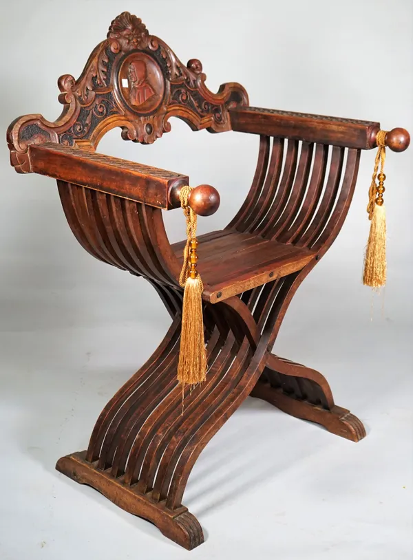 A 19th century carved walnut 'X' frame chair, the crest rail with Green man mask and carved figural bust, 70cm wide x 94cm high.