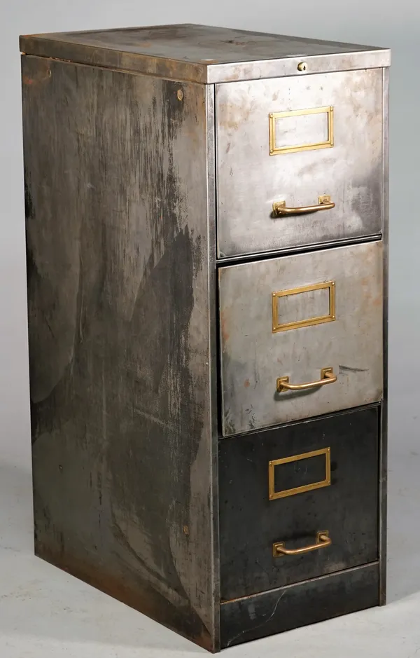 Industrial Design; a polished steel and brass three drawer filing cabinet, 39cm wide x 102cm high.